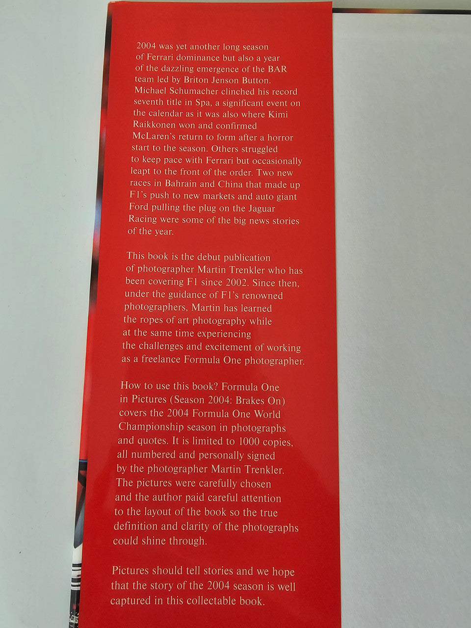 Motorsport photo book page with red background and paragraphs of publication text