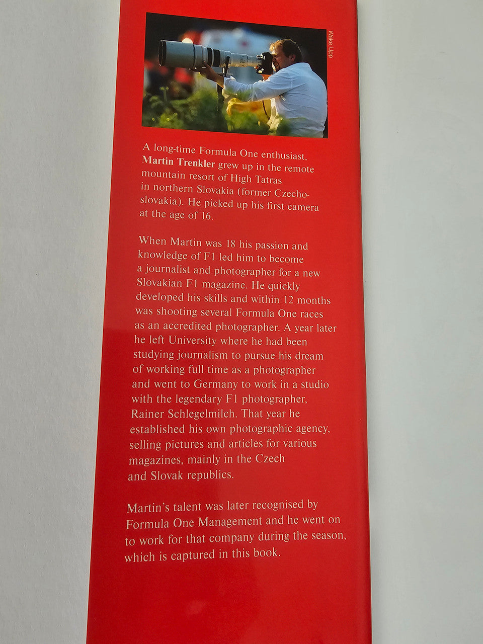 Motorsport photo book vertical page with red background and printed biography text