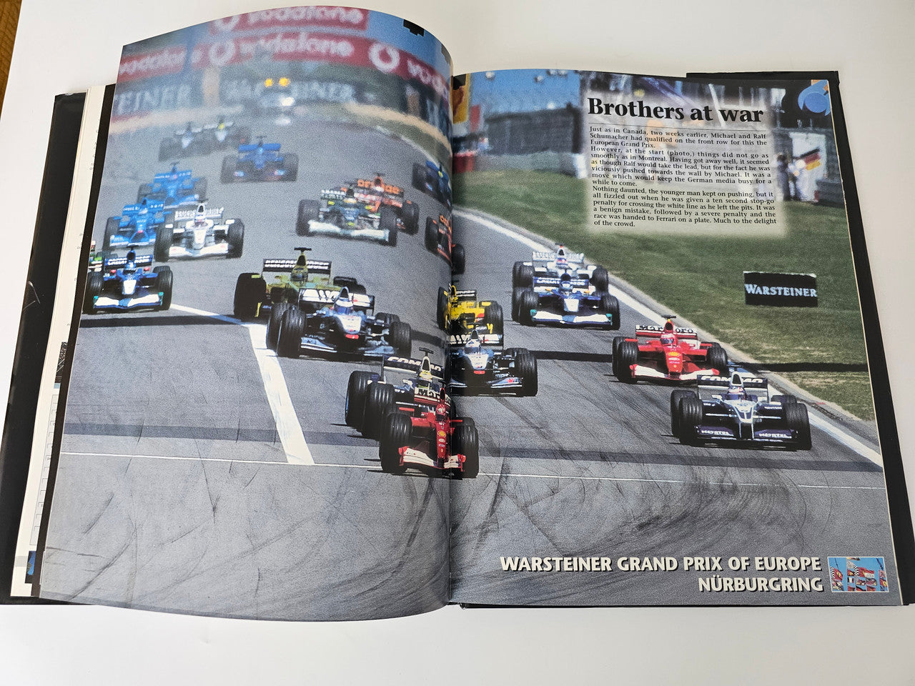Open motorsport yearbook with wide race photo spread on a track