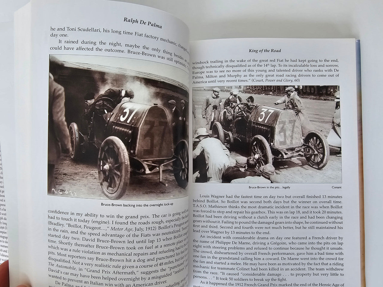 Open book spread with grayscale racing cars and printed paragraphs on both pages