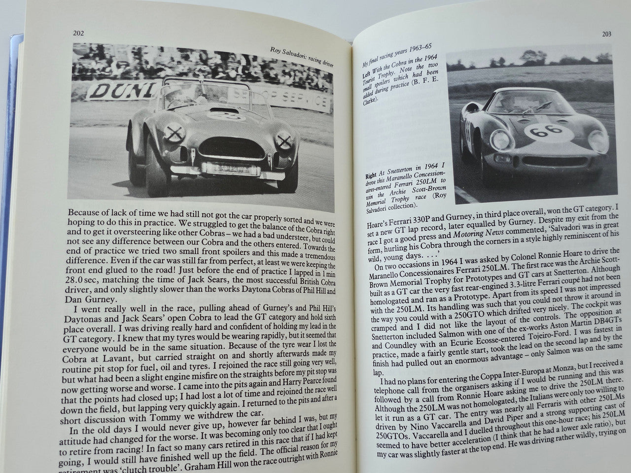 Open racing driver book page with two grayscale car photos and dense paragraph text.