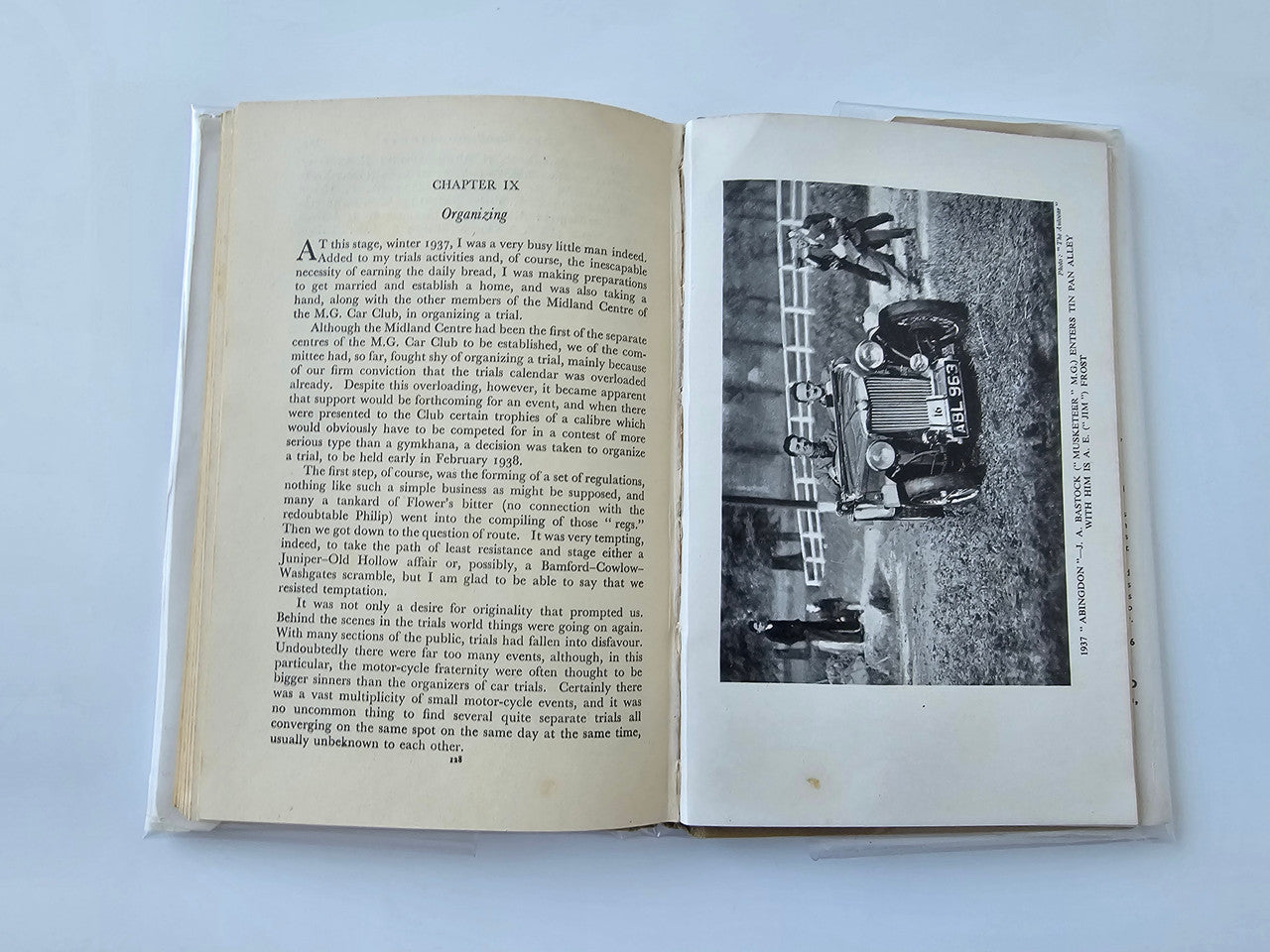 Vintage automotive book open to chapter page with black-and-white race photo