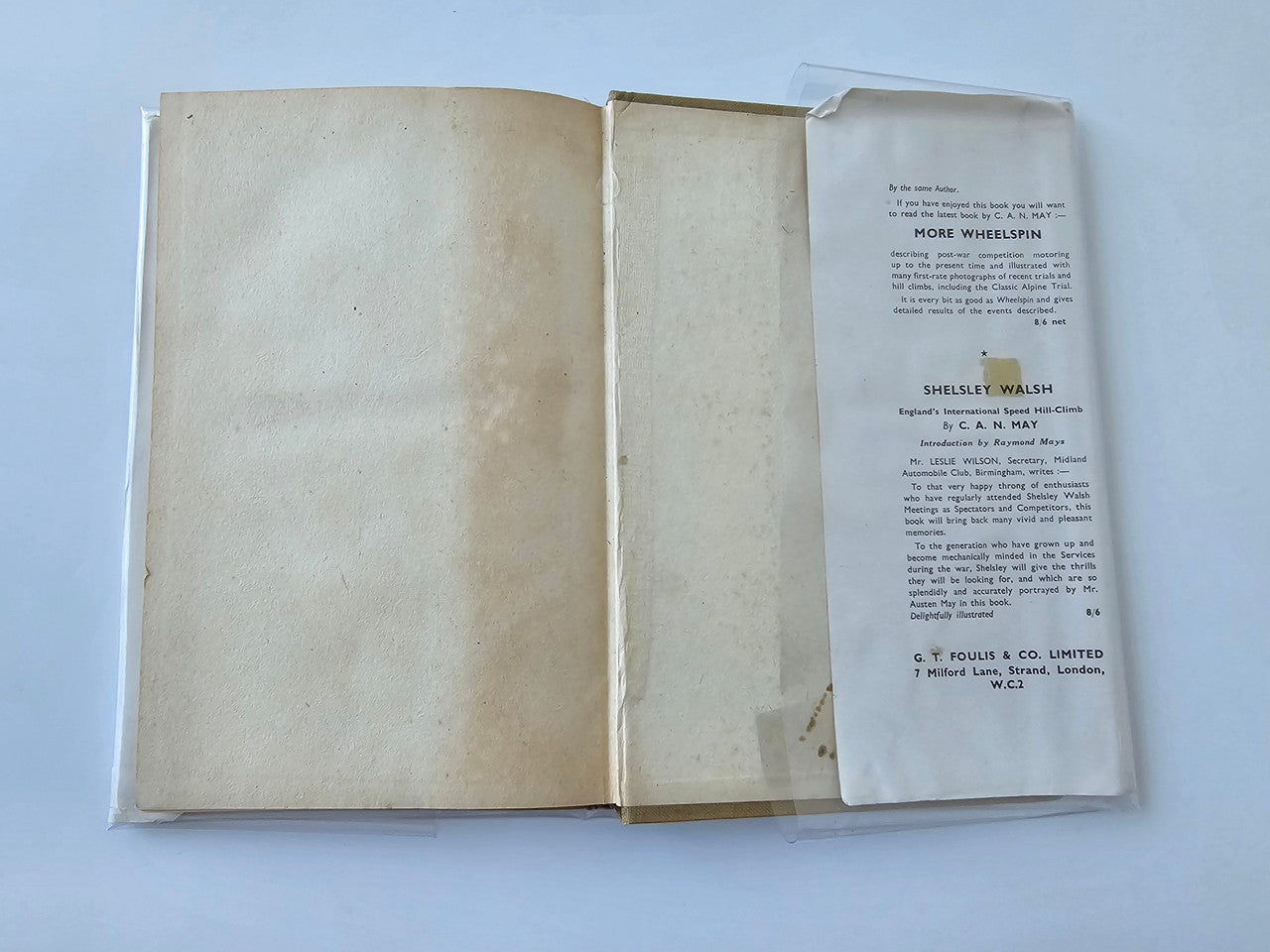 Vintage automotive book open, showing two blank pages and printed notice sheet