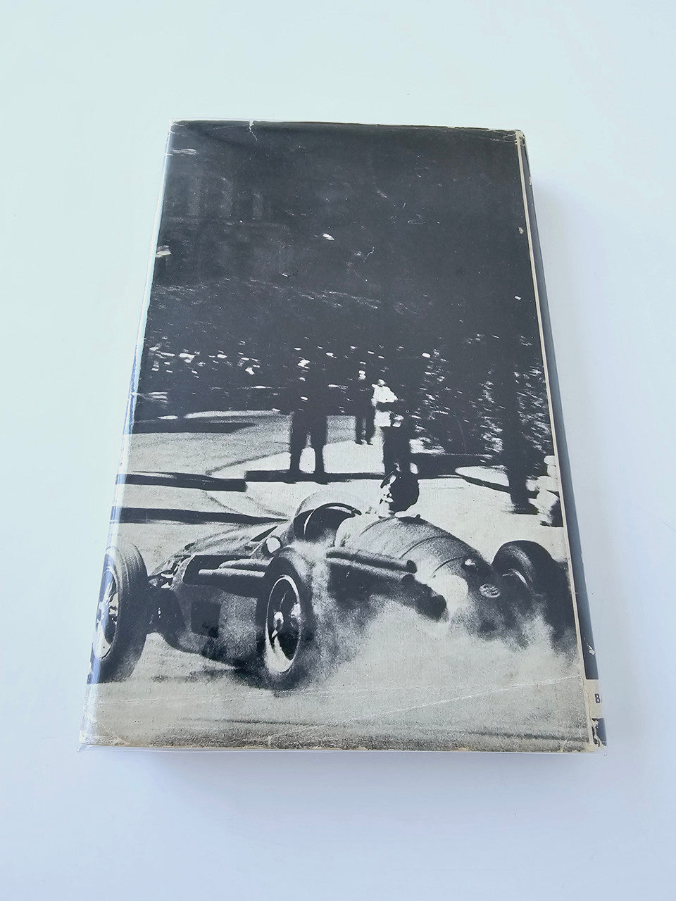 Racing Driver book back cover with black-and-white race car at the track