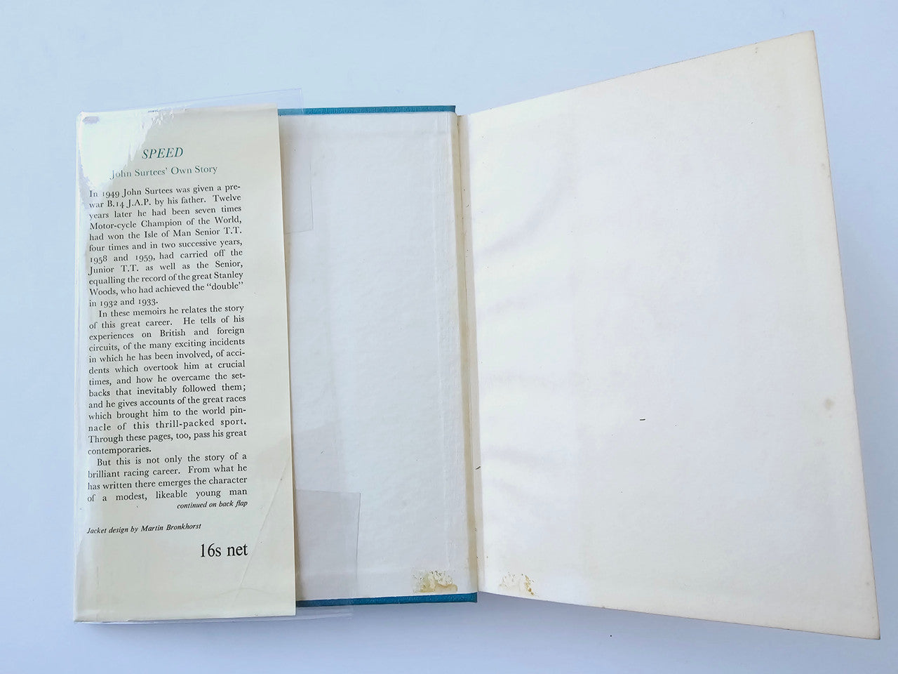 Motorsport memoir book open, cream pages with printed text and visible spine