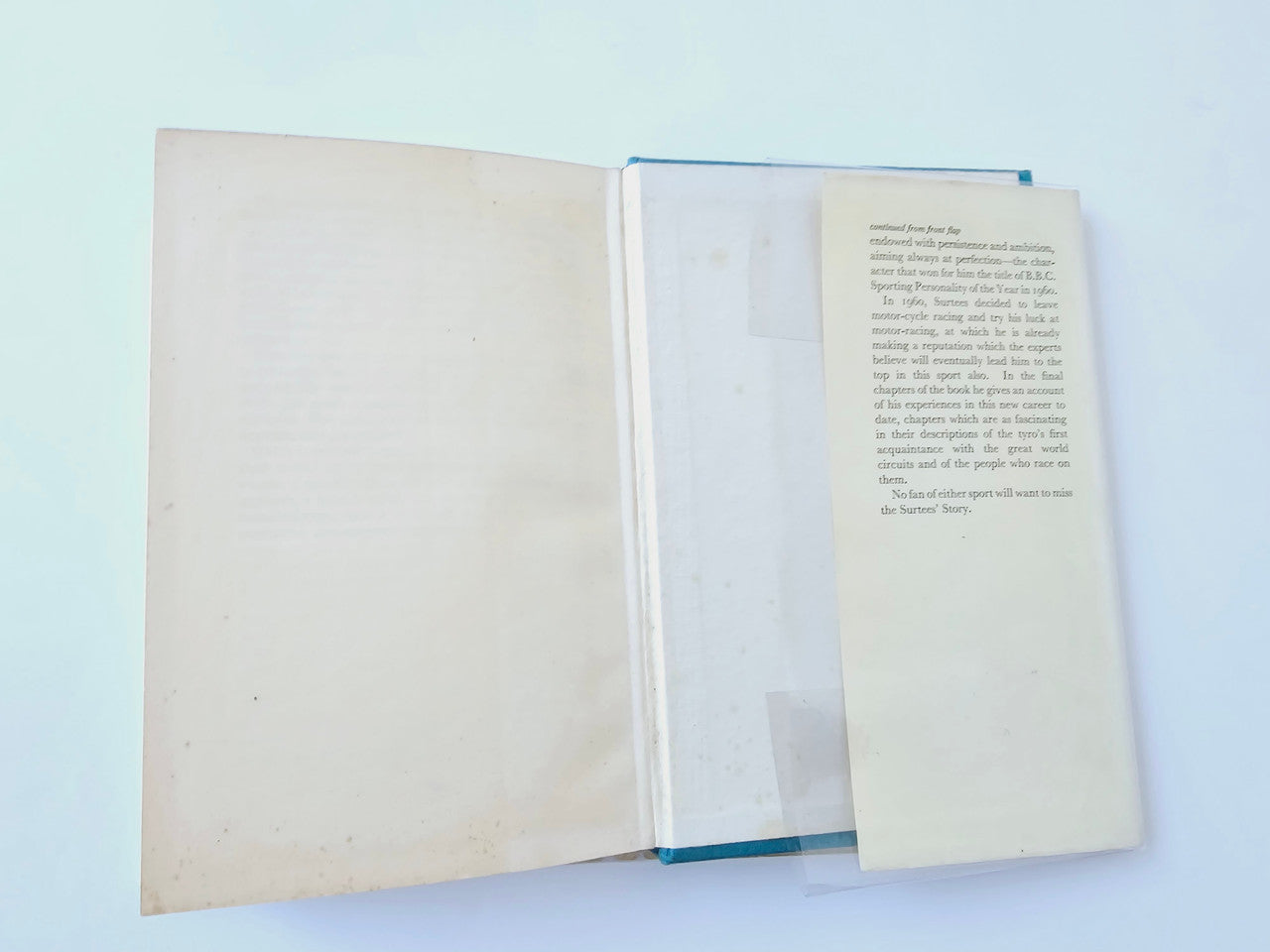Motorsport memoir book closed with small insert page laid on top, cream paper cover