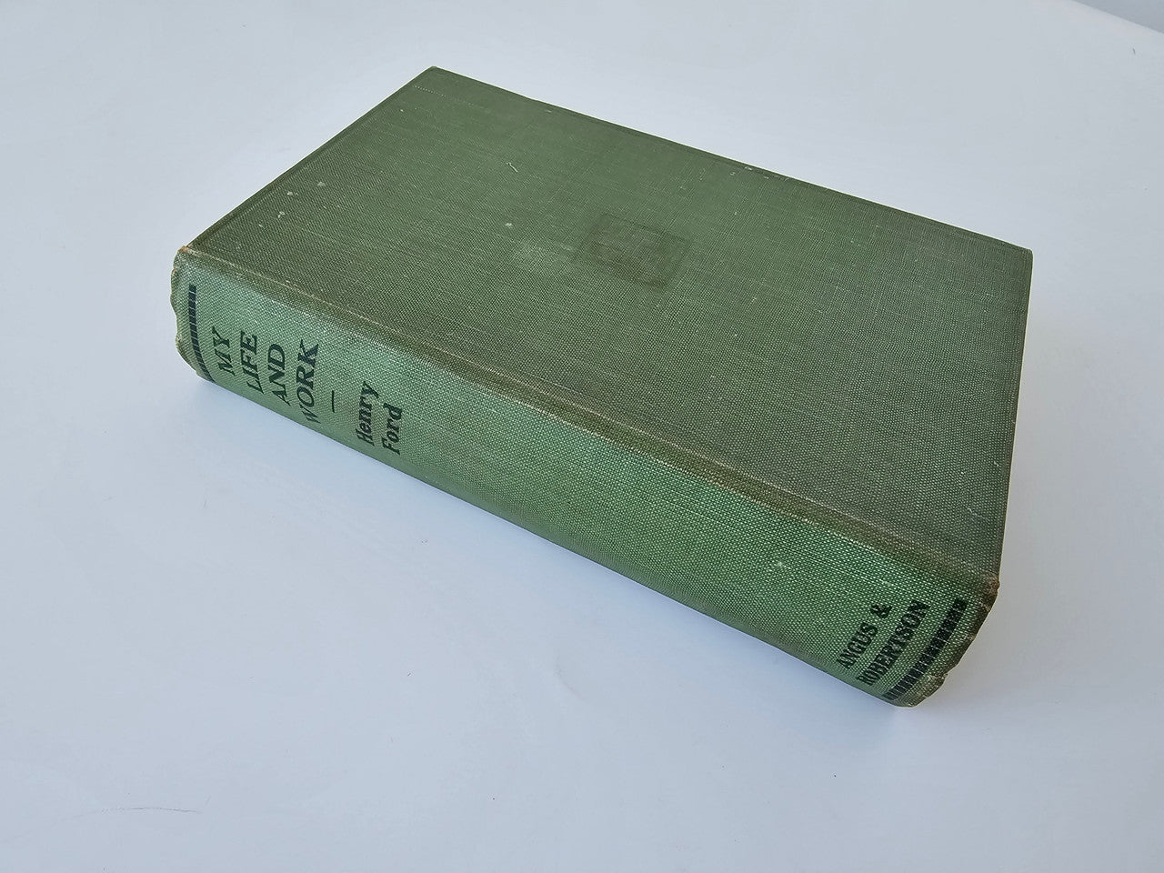 Green hardcover book closed, showing spine text and textured cloth cover.