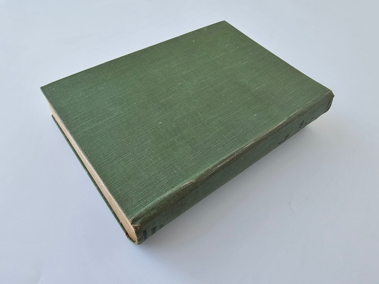 Green hardcover book with textured cloth cover, closed on its side.