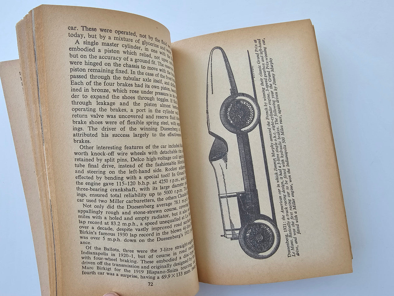 Open book page with dense text and a line drawing of a racing car part