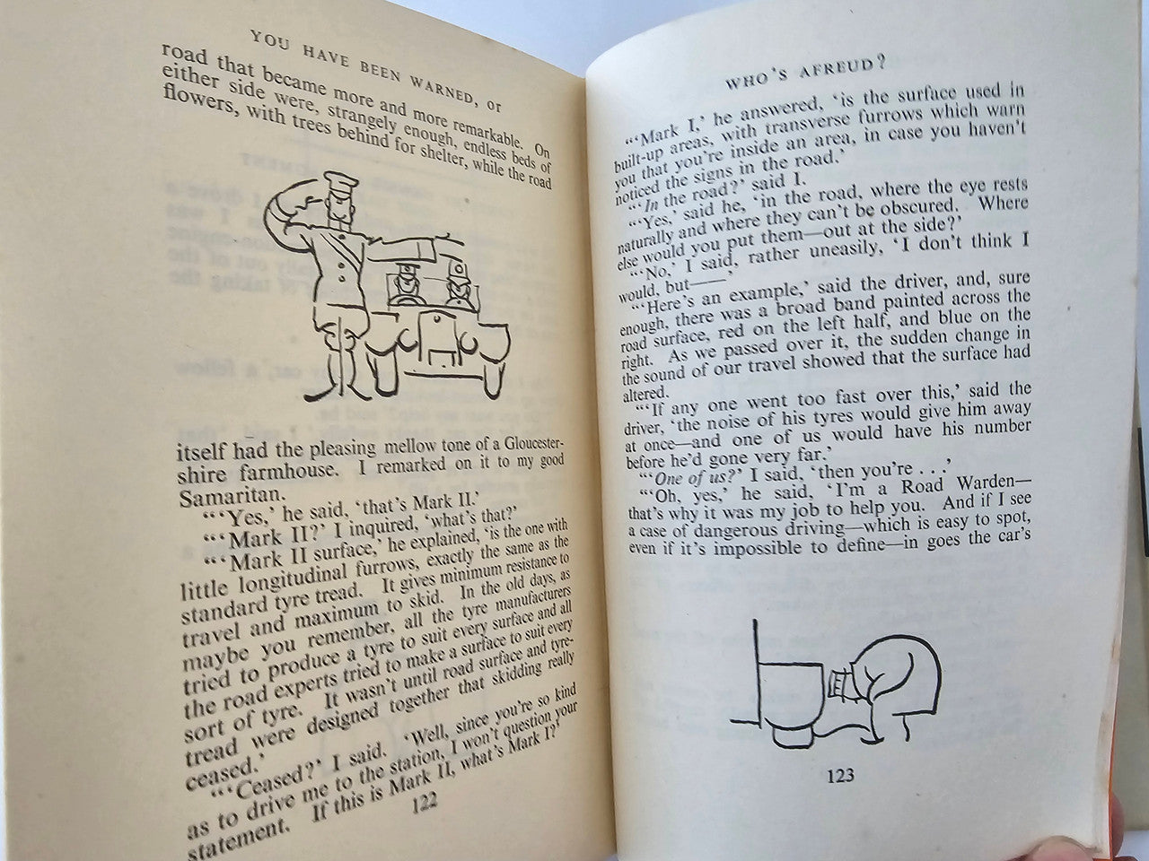 Vintage book open to illustrated dialogue pages with small diagrams