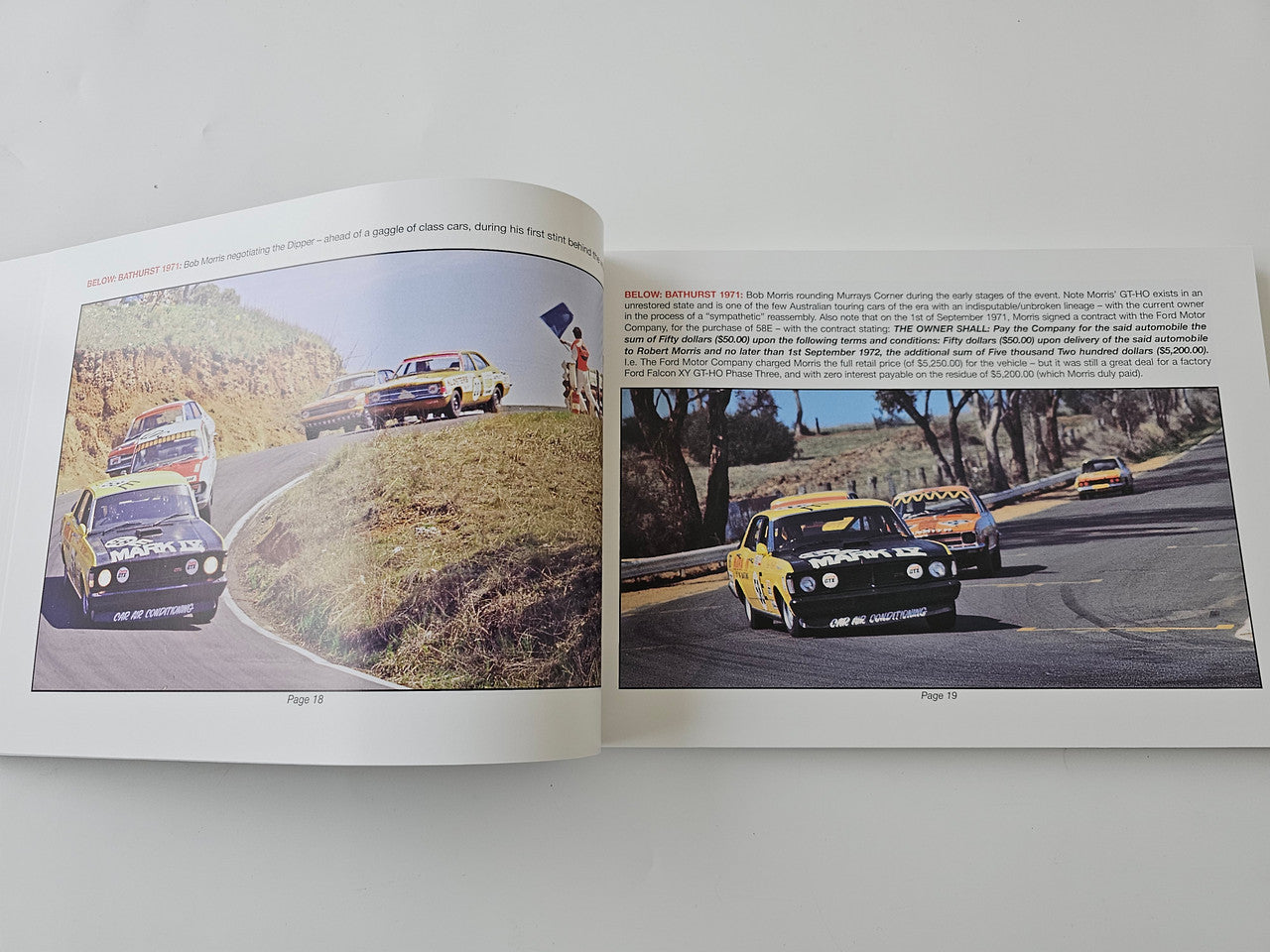 Paperback book open to two-page race photo spread with cars on winding road