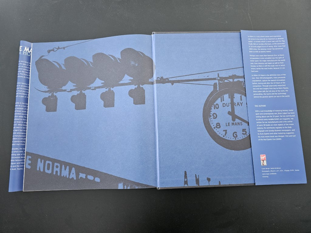 Open book pages with large gray car silhouettes and circular track graphic