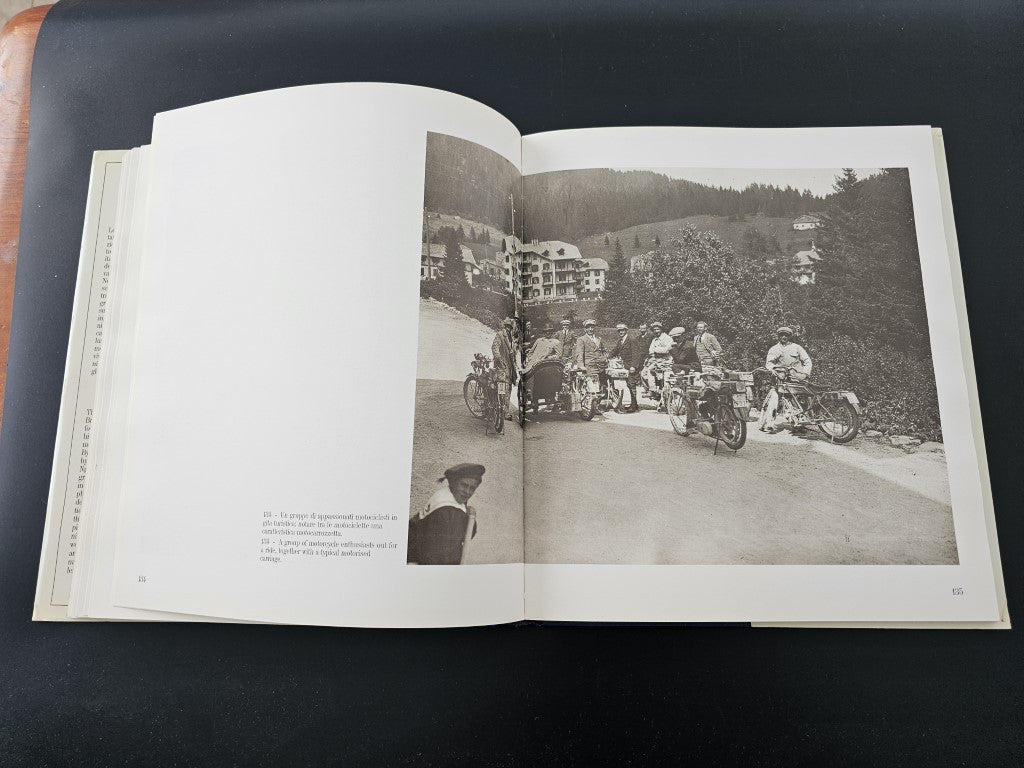 Open book with black-and-white outdoor photo of vehicles, riders and crowds