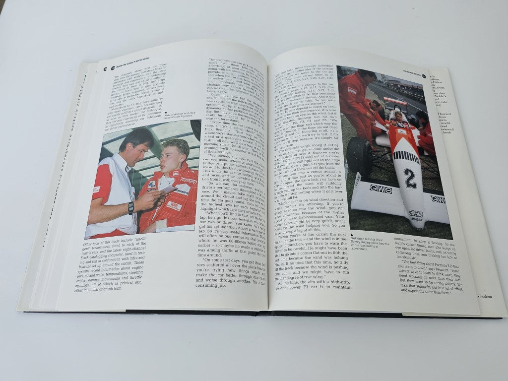 Open motor racing book with text columns and red race car photos on two pages