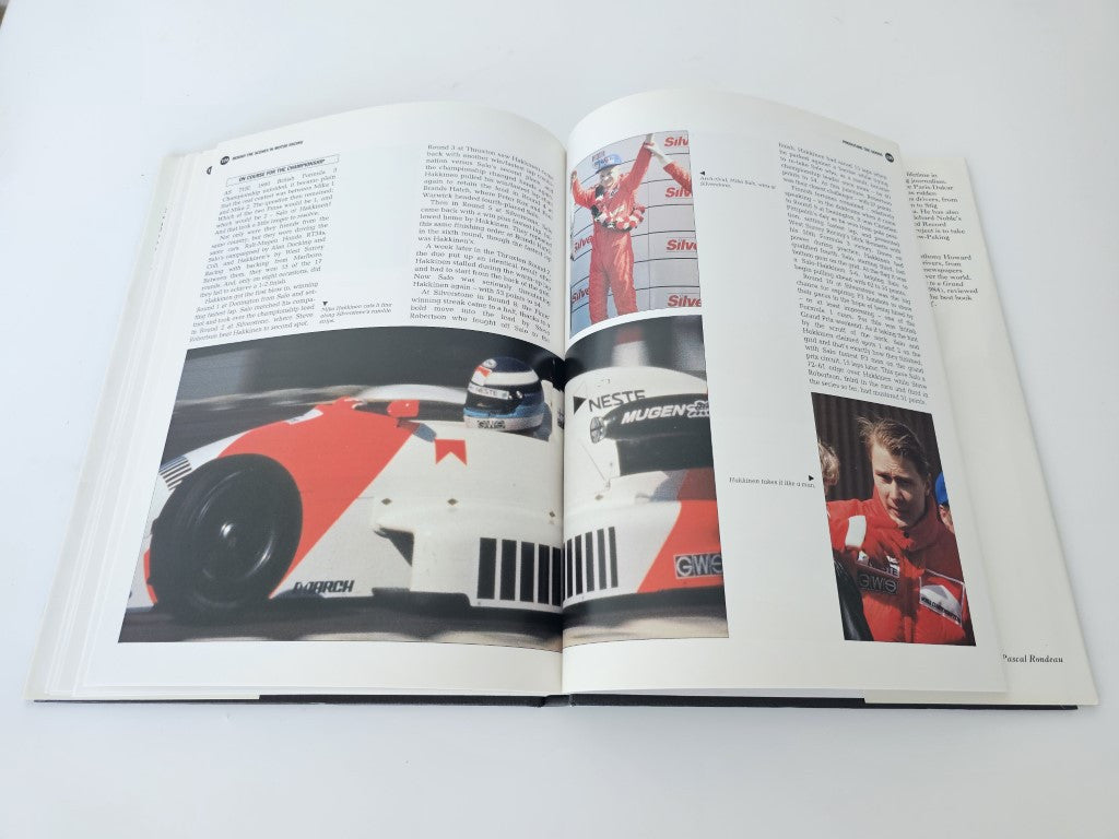 Open motor racing book with large red car photo and smaller portrait on right page