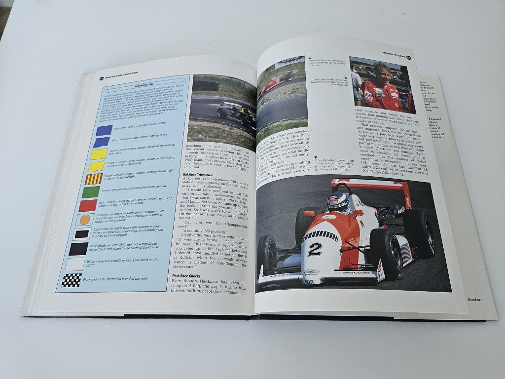 Open motor racing book showing stats table and close-up red race car photo spread