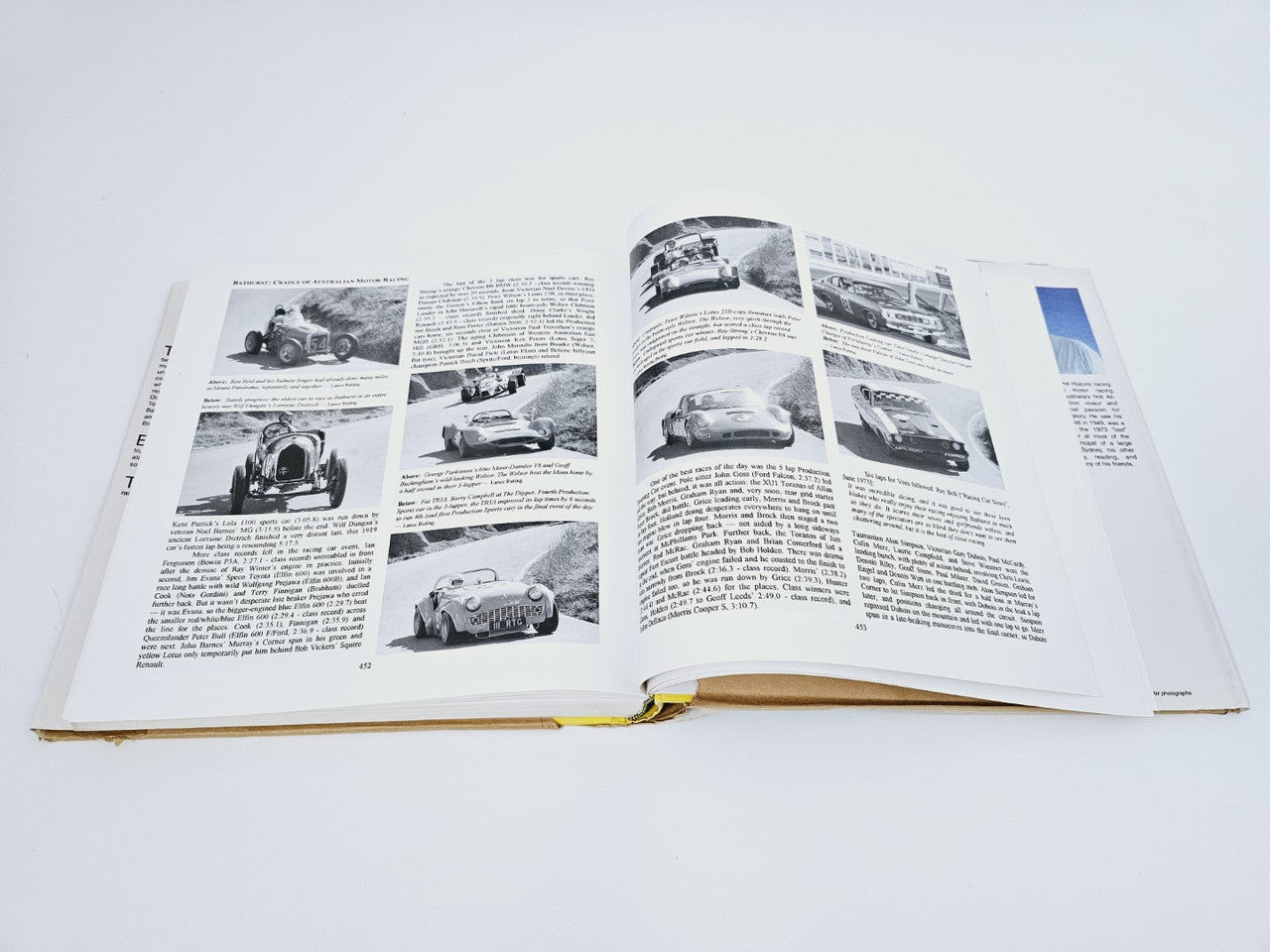 Open hardcover book with multiple racing car photo plates and article text