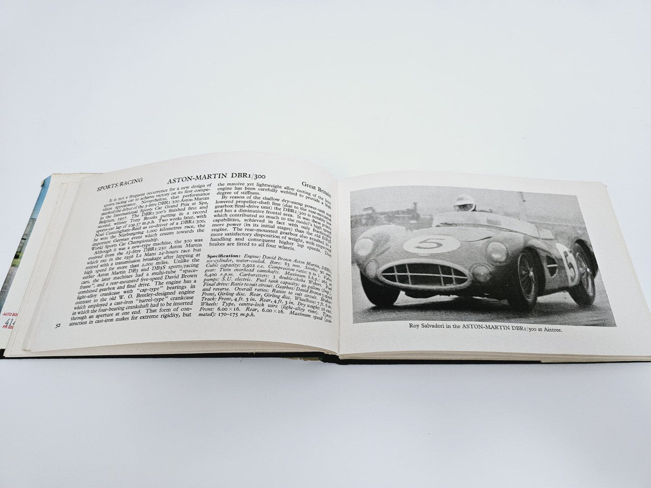 Open book page with dense text on the left and a race car photo on the right