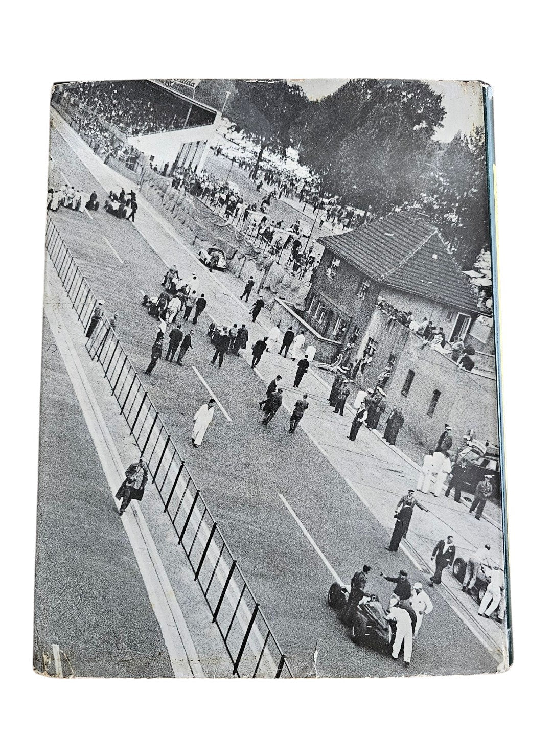 Vintage auto racing book with black-and-white photo of spectators along a track.