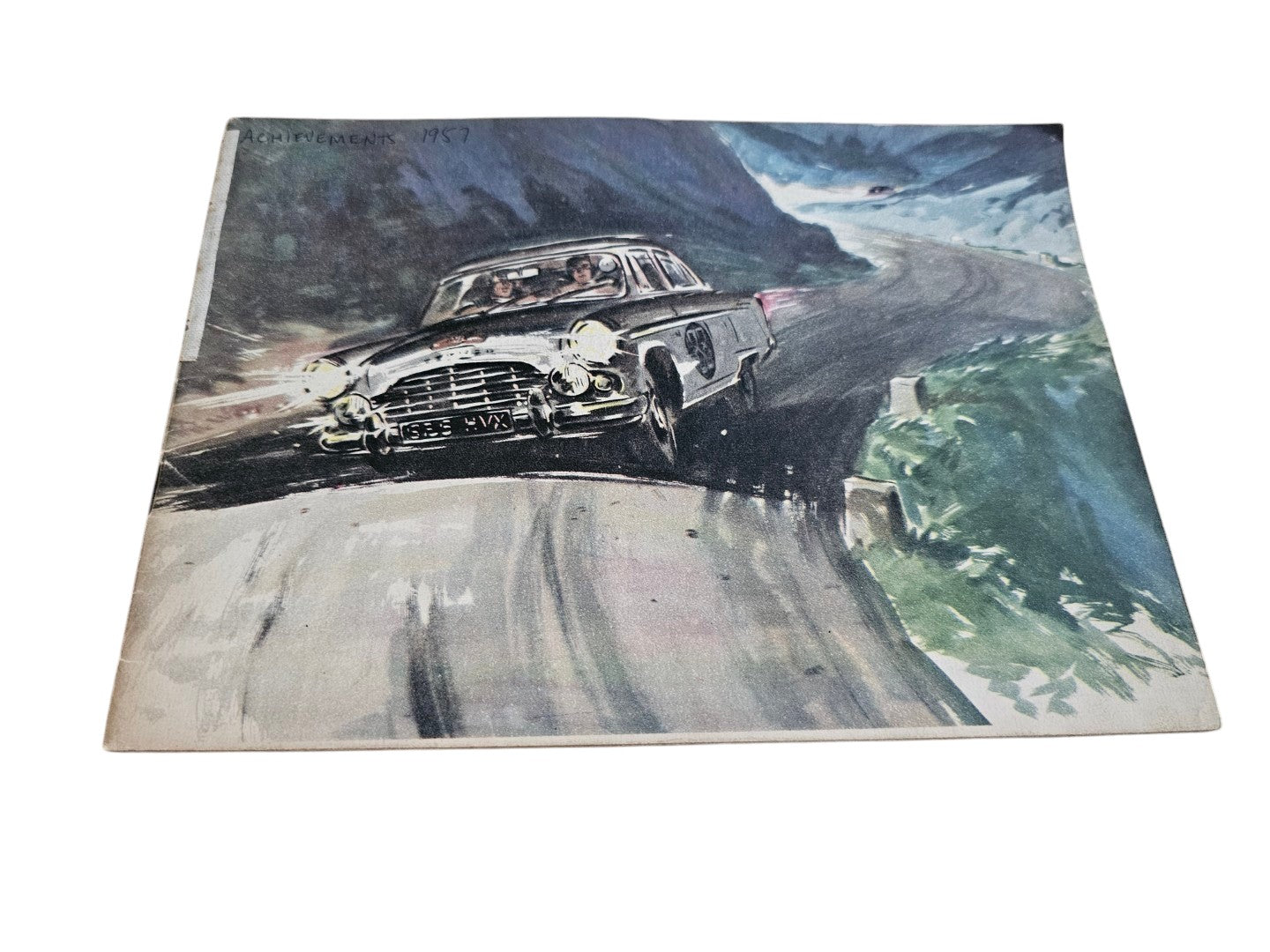 Vintage racing illustration of a classic black car rounding a mountain road