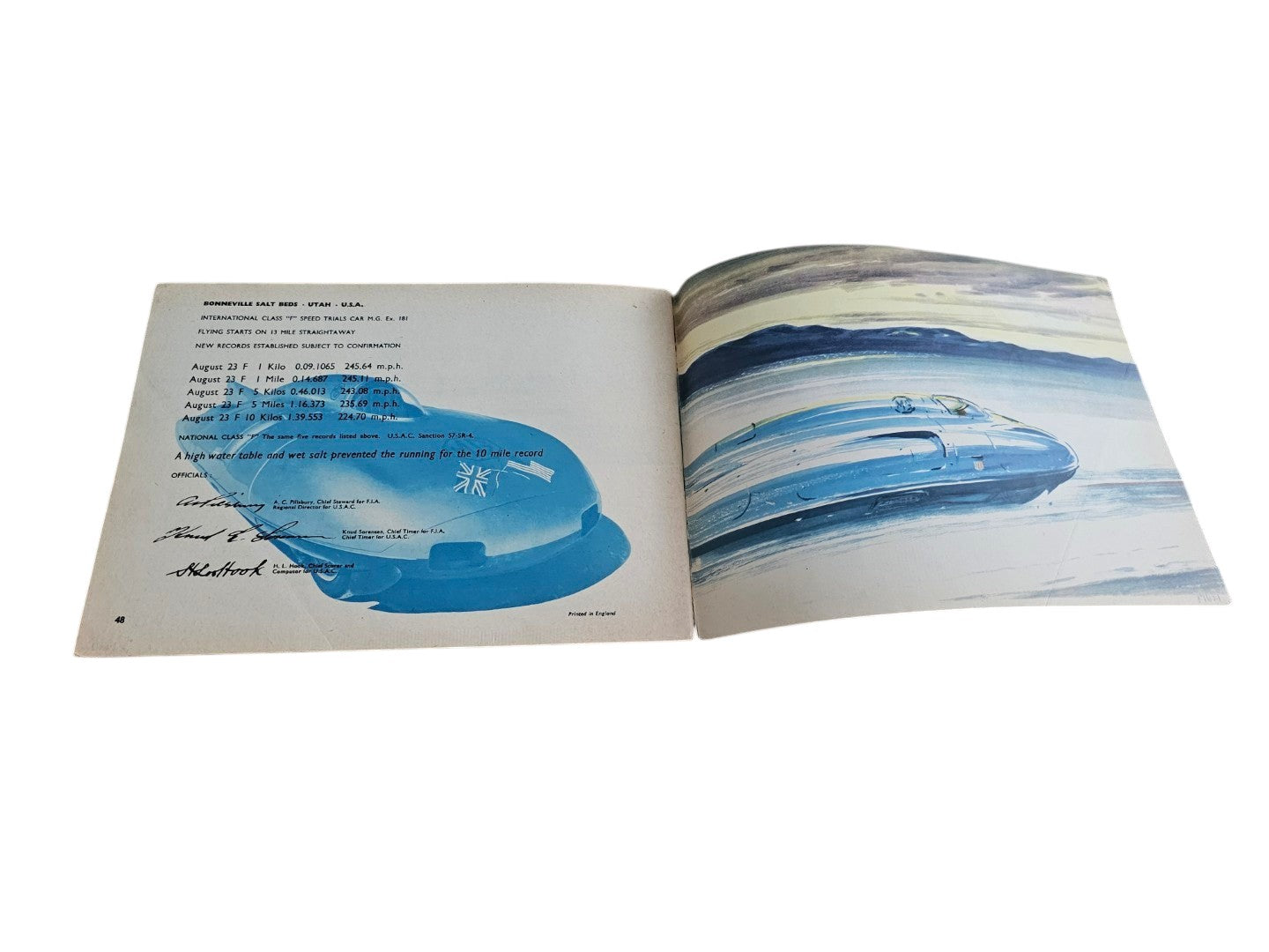 Open vintage racing book with a blue vehicle painting and text page