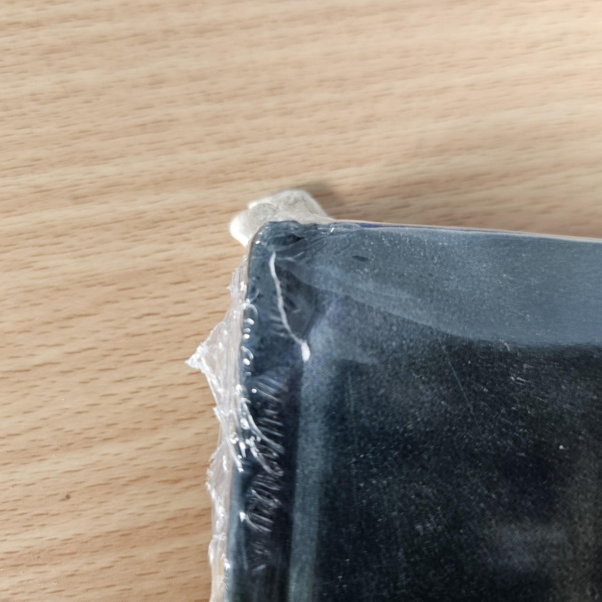 Book with dark cover, torn plastic wrap and exposed corner