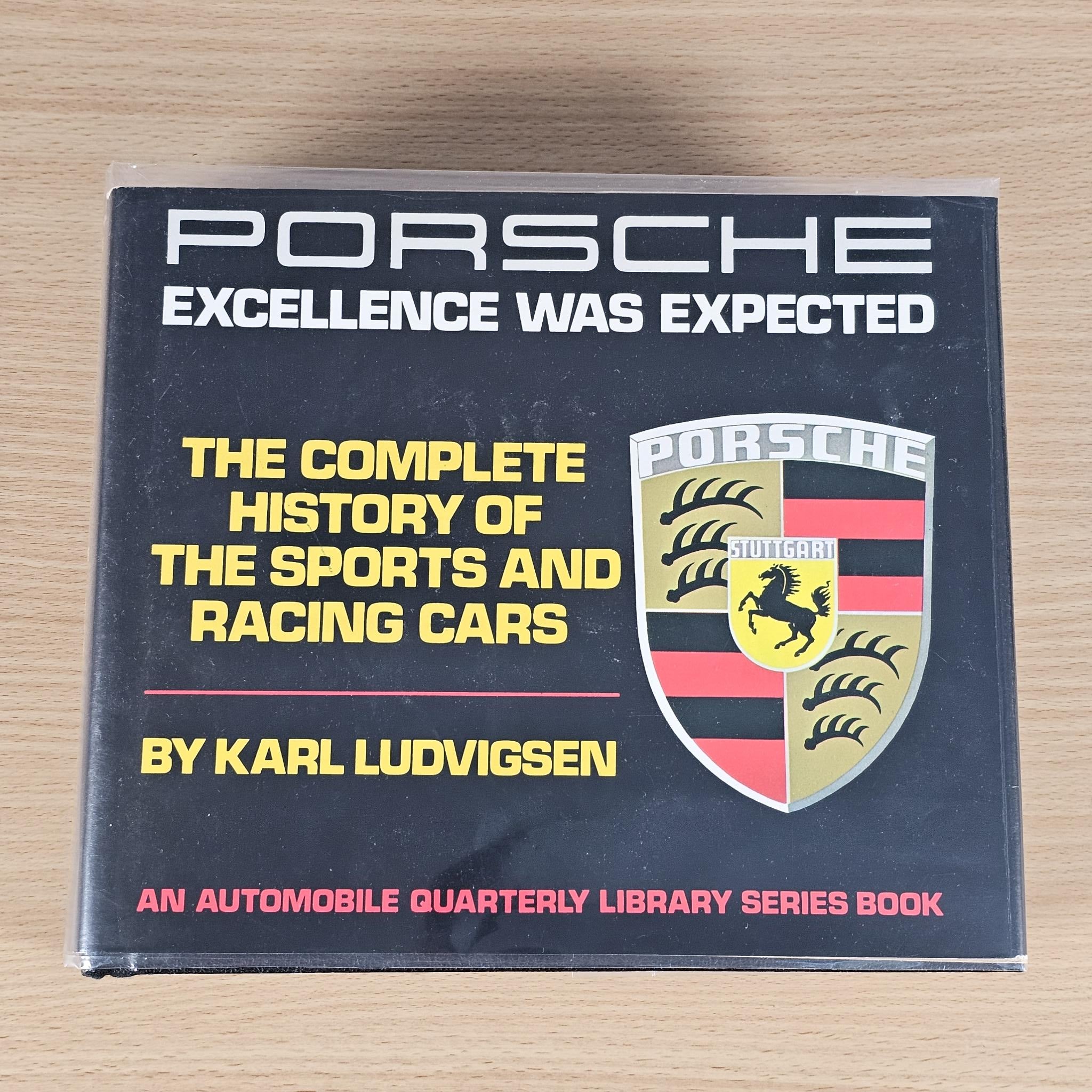 Automobile history book with dark cover, Porsche crest and yellow title lettering