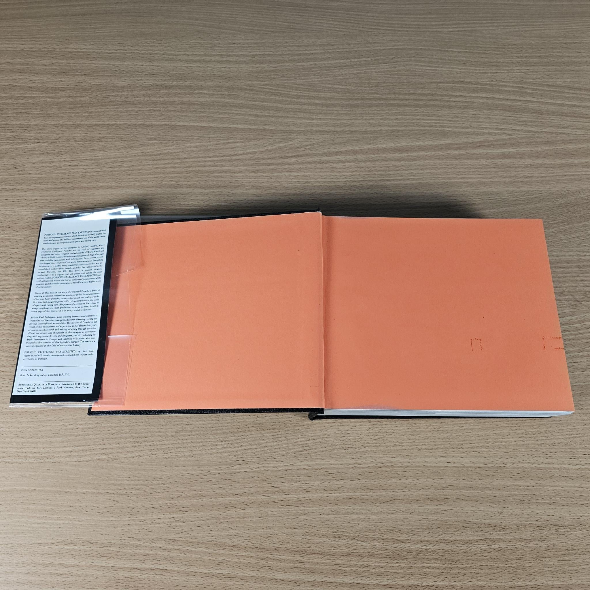 Automobile history book open to orange-toned pages with black binding spine