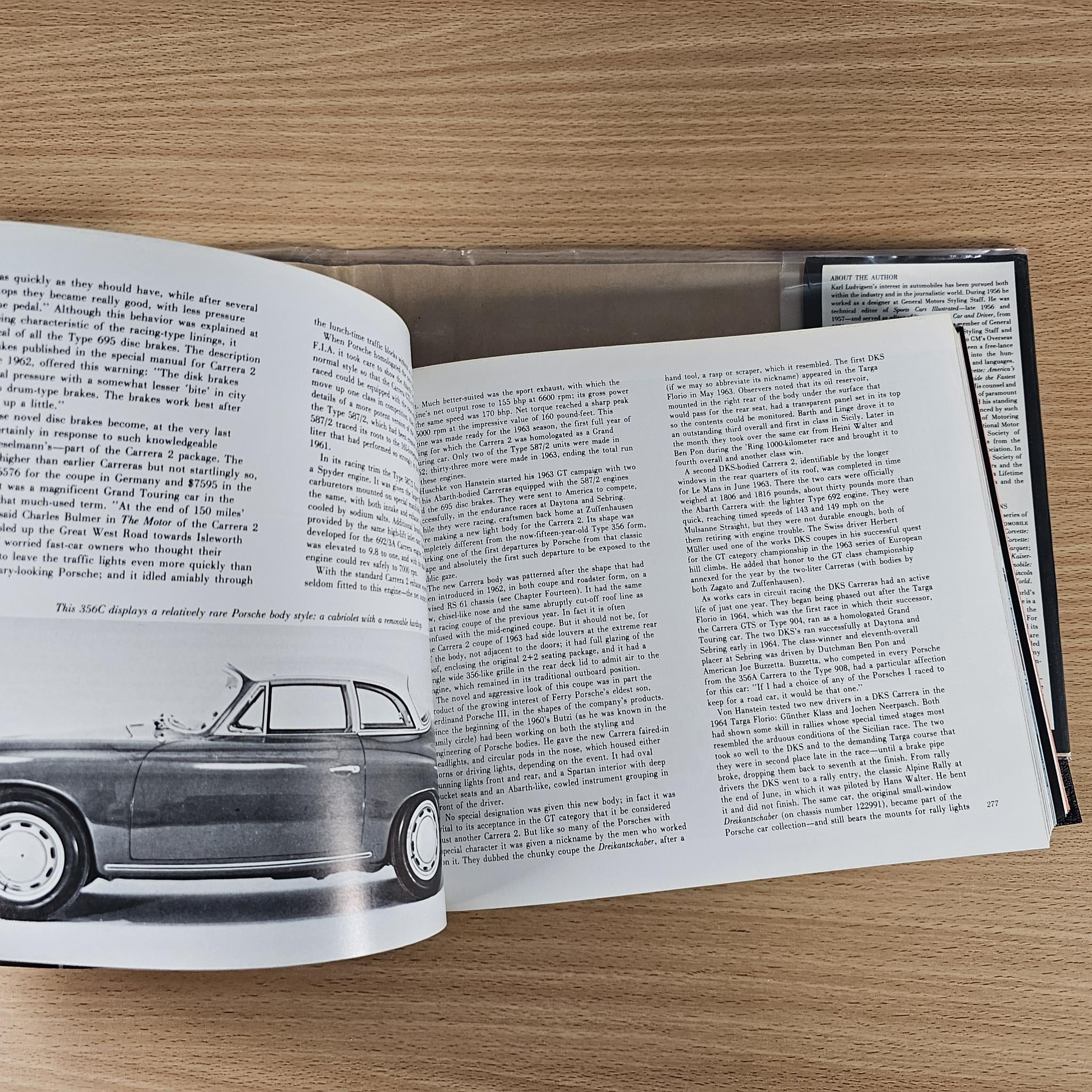 Automobile history book open to illustrated page with classic car drawing and text