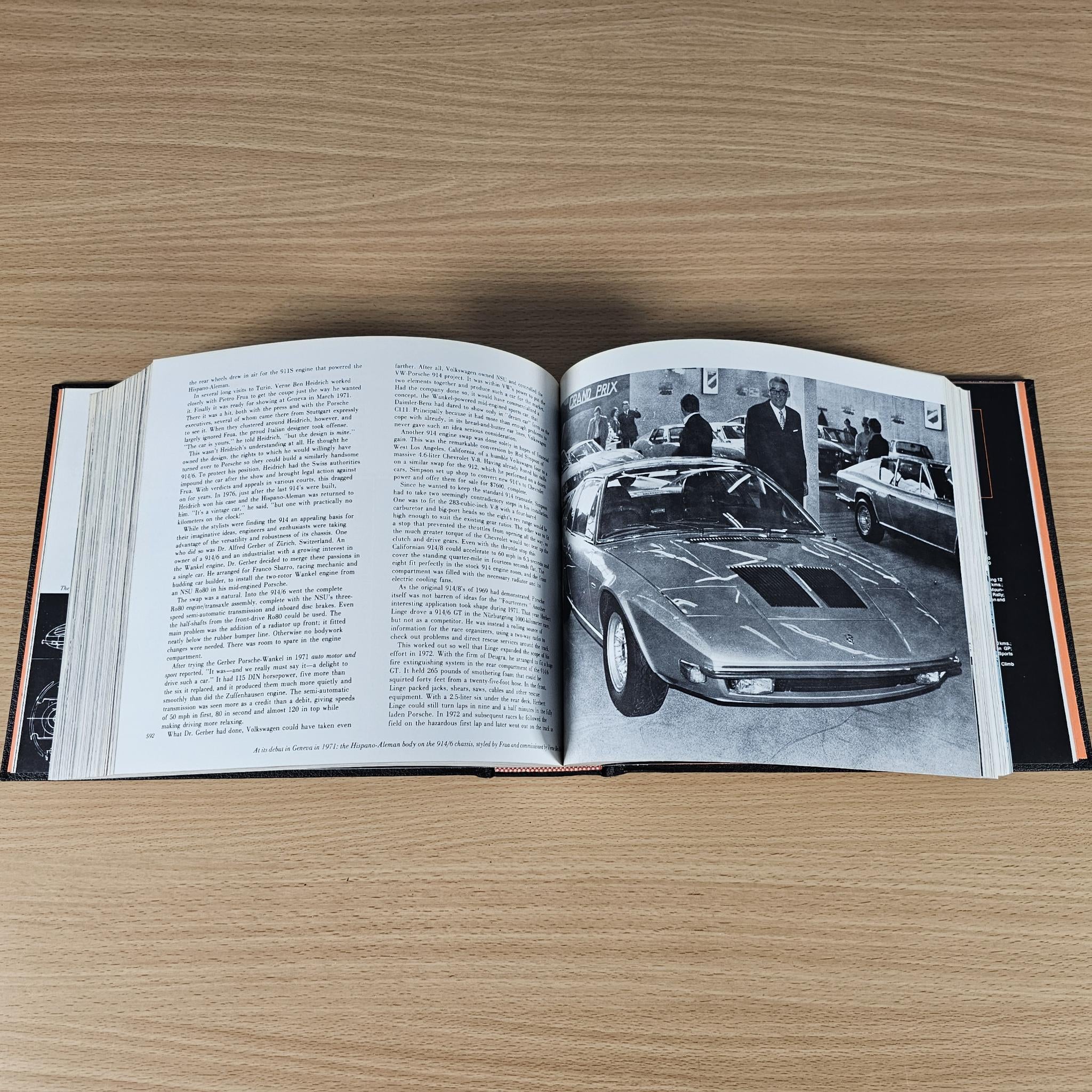 Open book featuring black-and-white sports car photos and printed text pages.