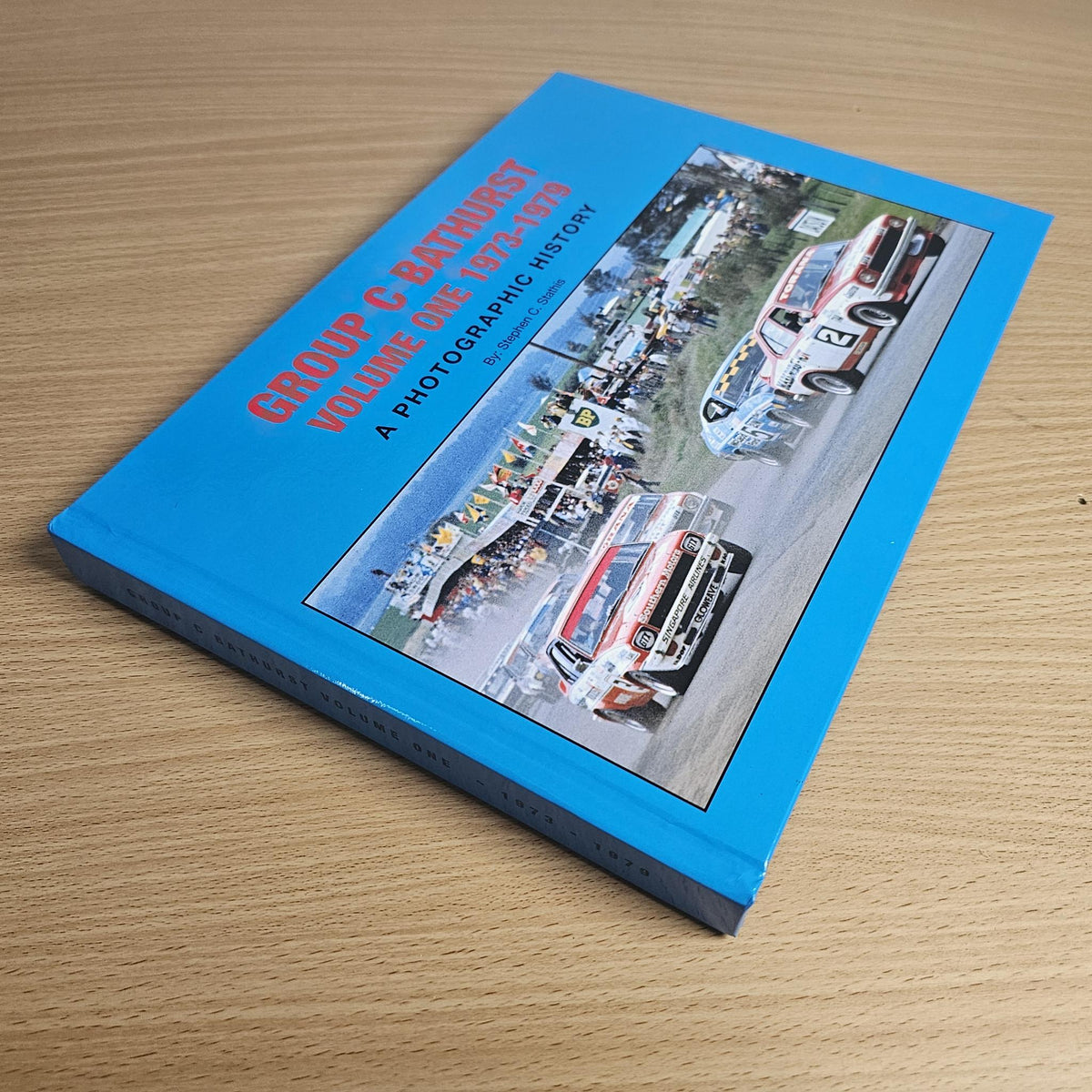 Blue racing photo history book with car collage on the cover