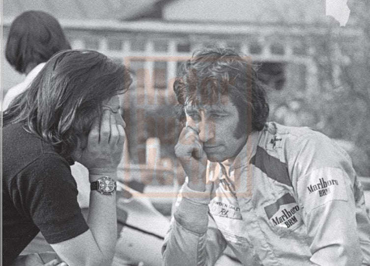 Motorsport book page with two people talking beside a race car