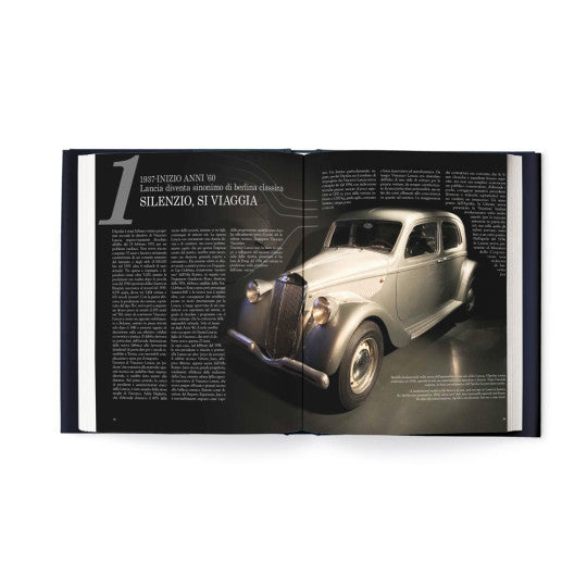 Open book spread with silver vintage car and driver steering wheel scene