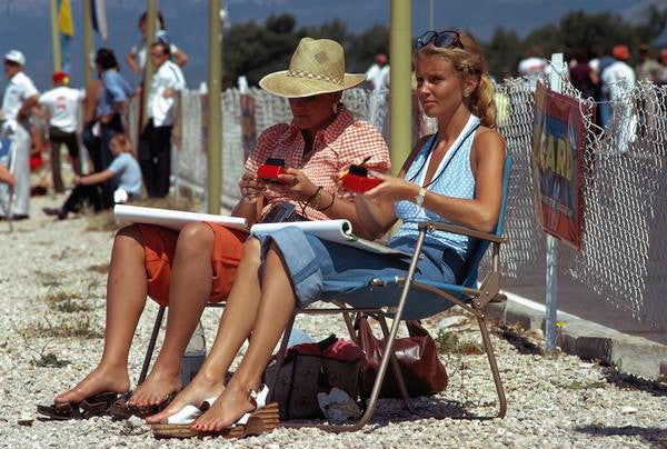 Formula 1 1970s book page with people seated on folding chairs by a racing track