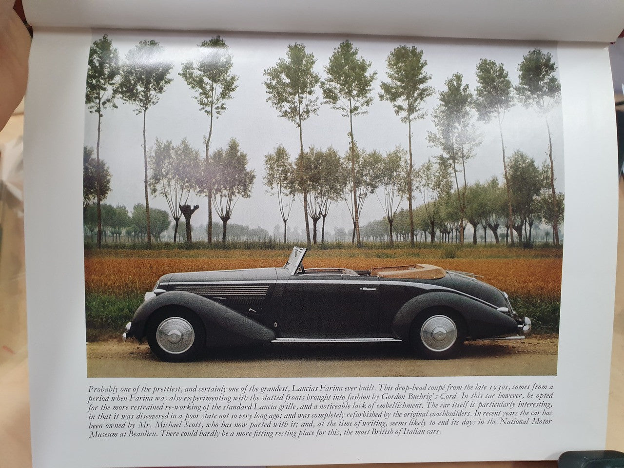 Single page photo of a classic dark convertible car in an outdoor field