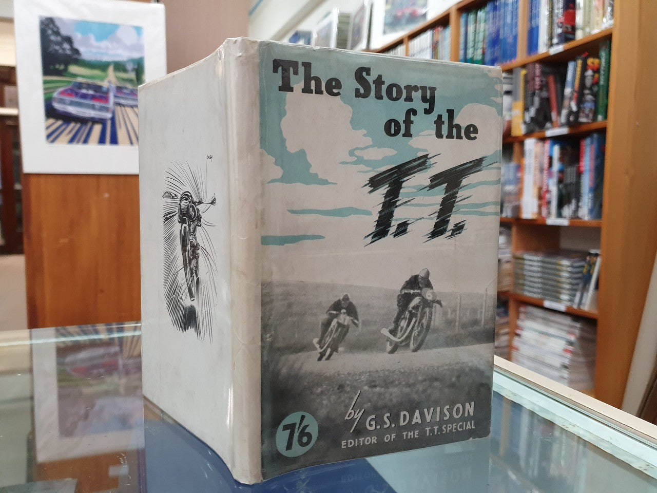 Hardcover book “The Story of the T.T.” displayed on a glass table; full front cover.