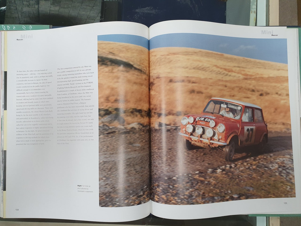 Hardcover photo book with open pages, showing a red Mini car on a dirt road