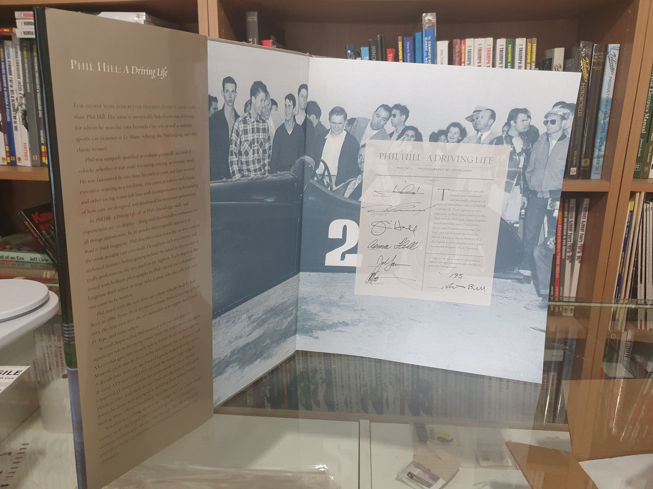 Open hardcover book spread with photo panels and a signed document insert