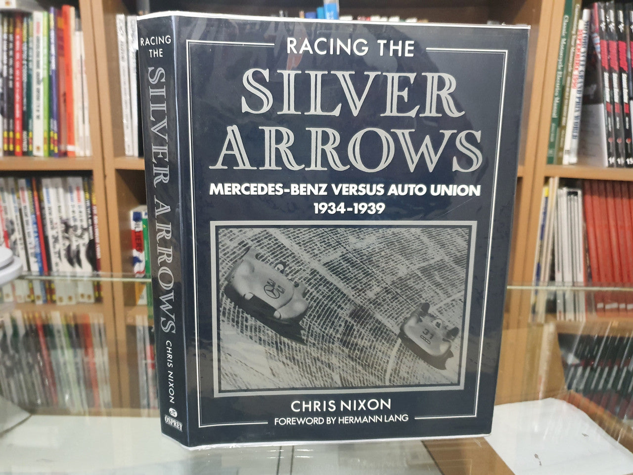 Dark blue hardcover book on shelf with Racing the Silver Arrows front cover