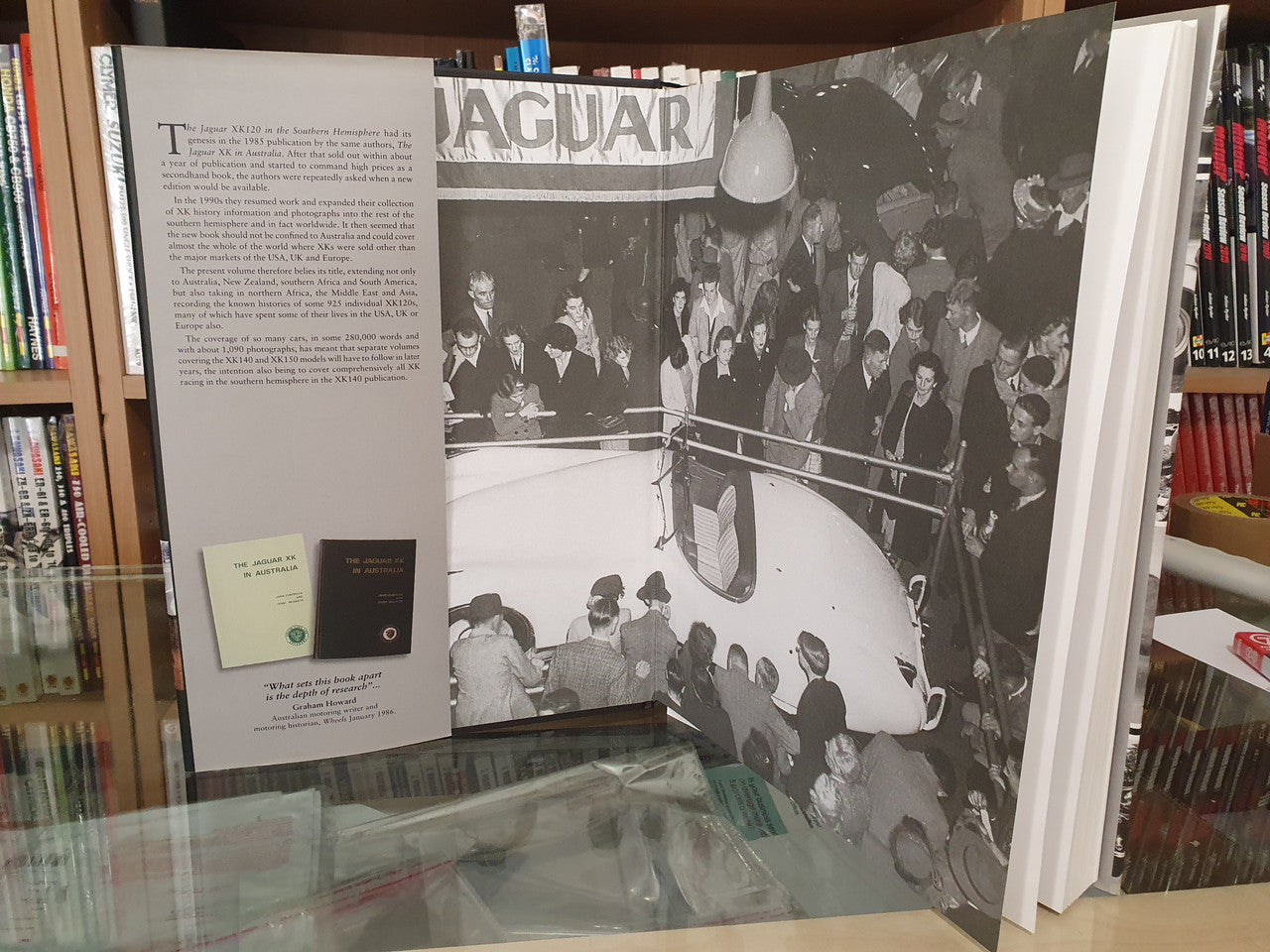 Open book spread with black-and-white Jaguar XK120 group photo and printed text.