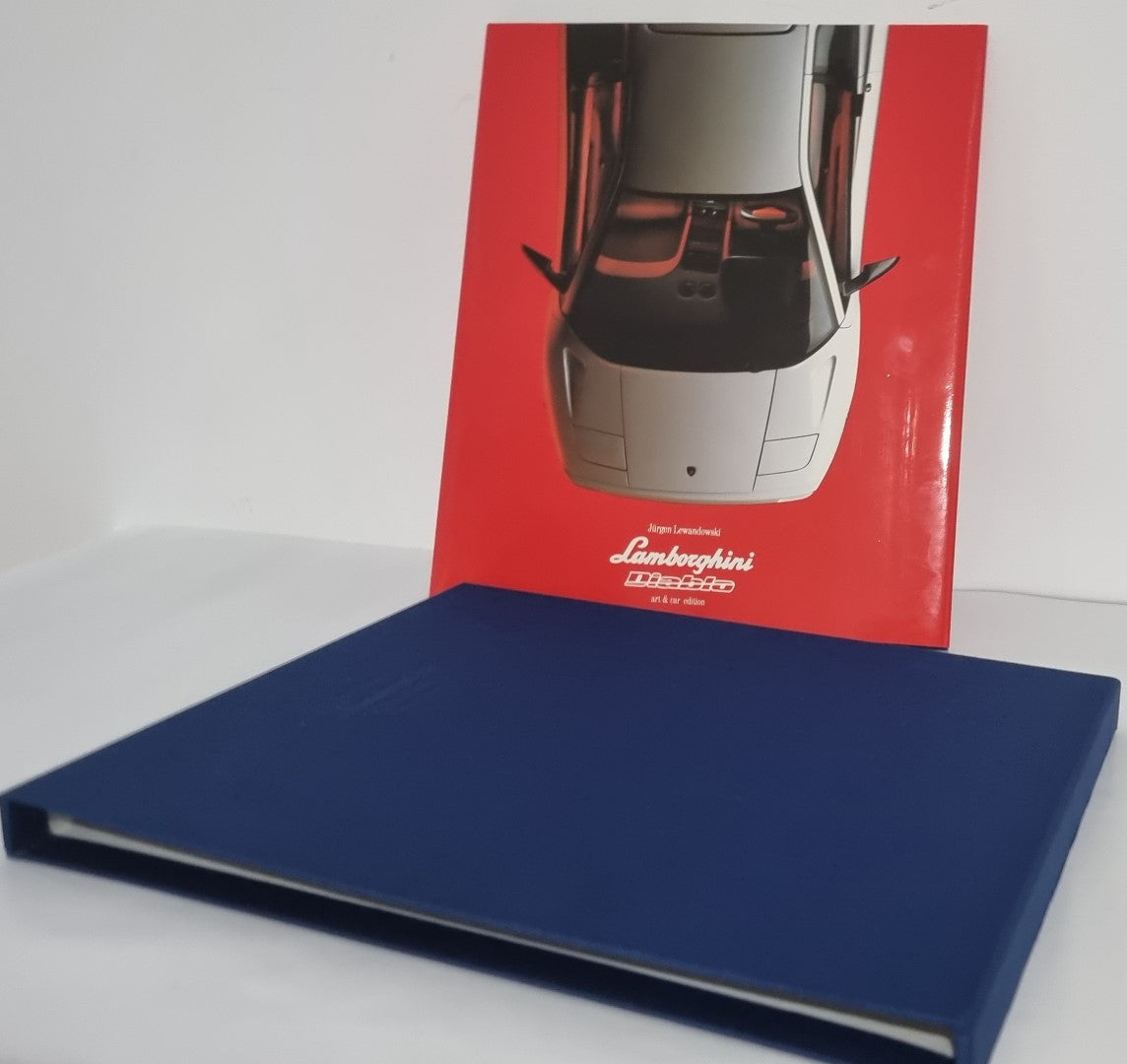 Lamborghini art slipcase box with red cover and blue base, book resting nearby