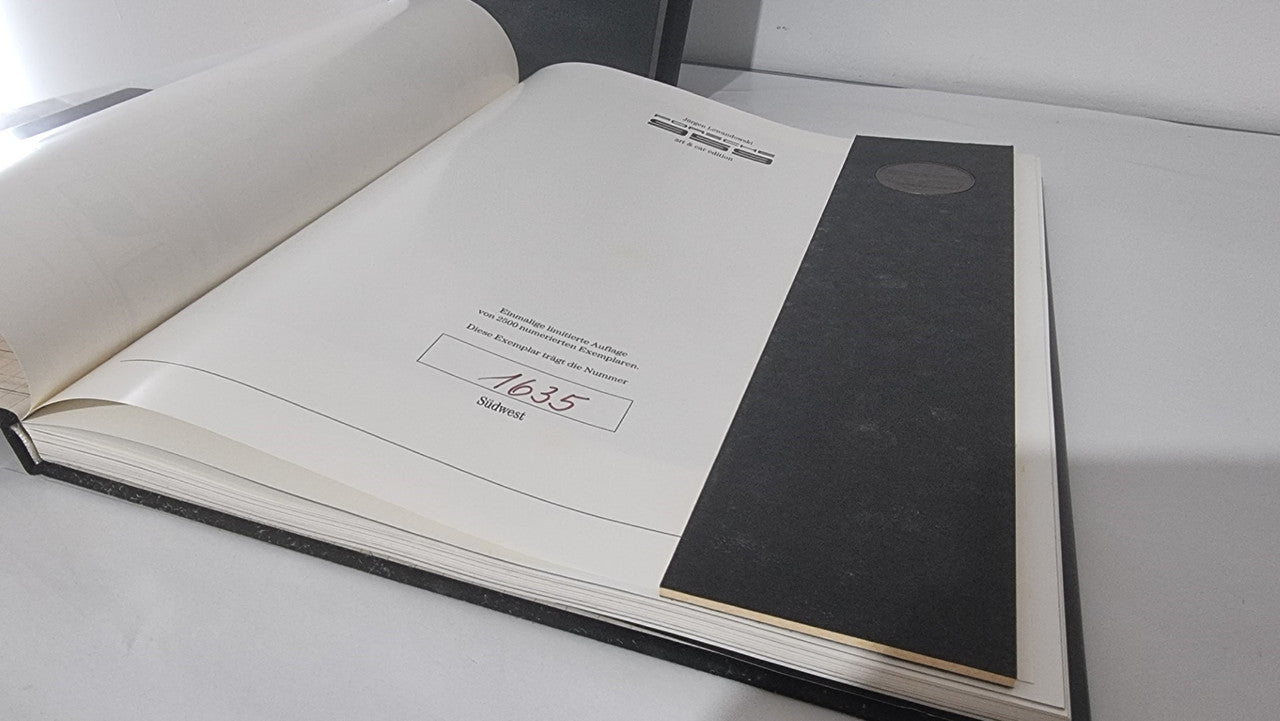 Open art book with illustrated front panel and surrounding text pages