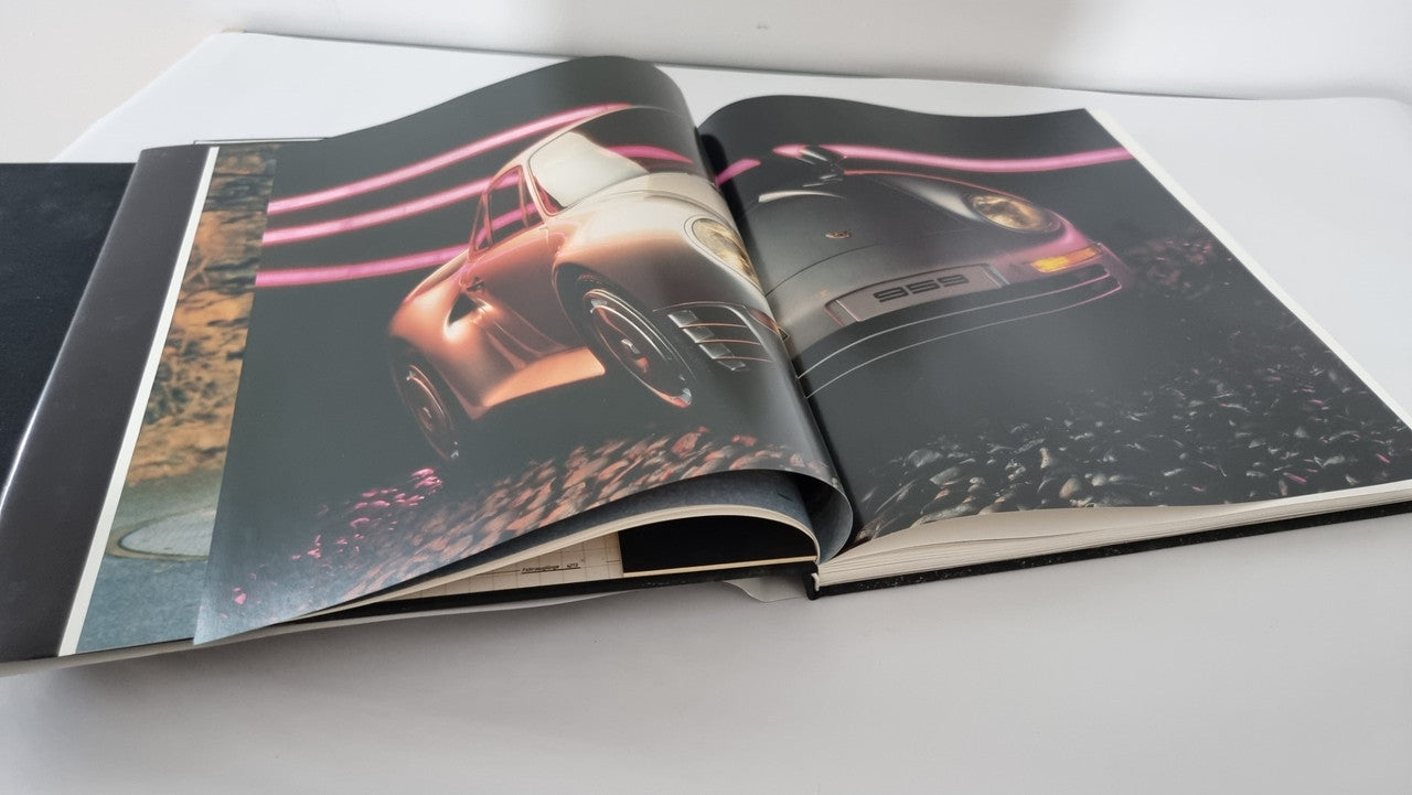 Open art book showing two-page car photo spread with dark background