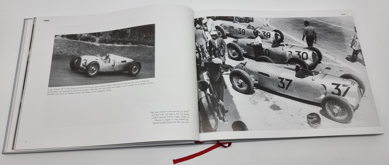 Open photo album showing black-and-white race cars on two pages, with red ribbon