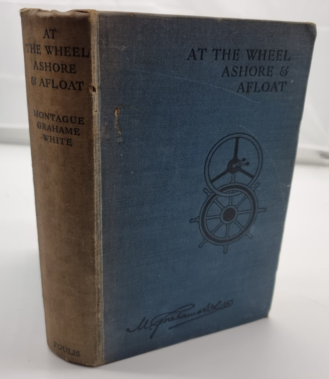 Blue hardcover book with narrow spine and wheel emblem on front cover