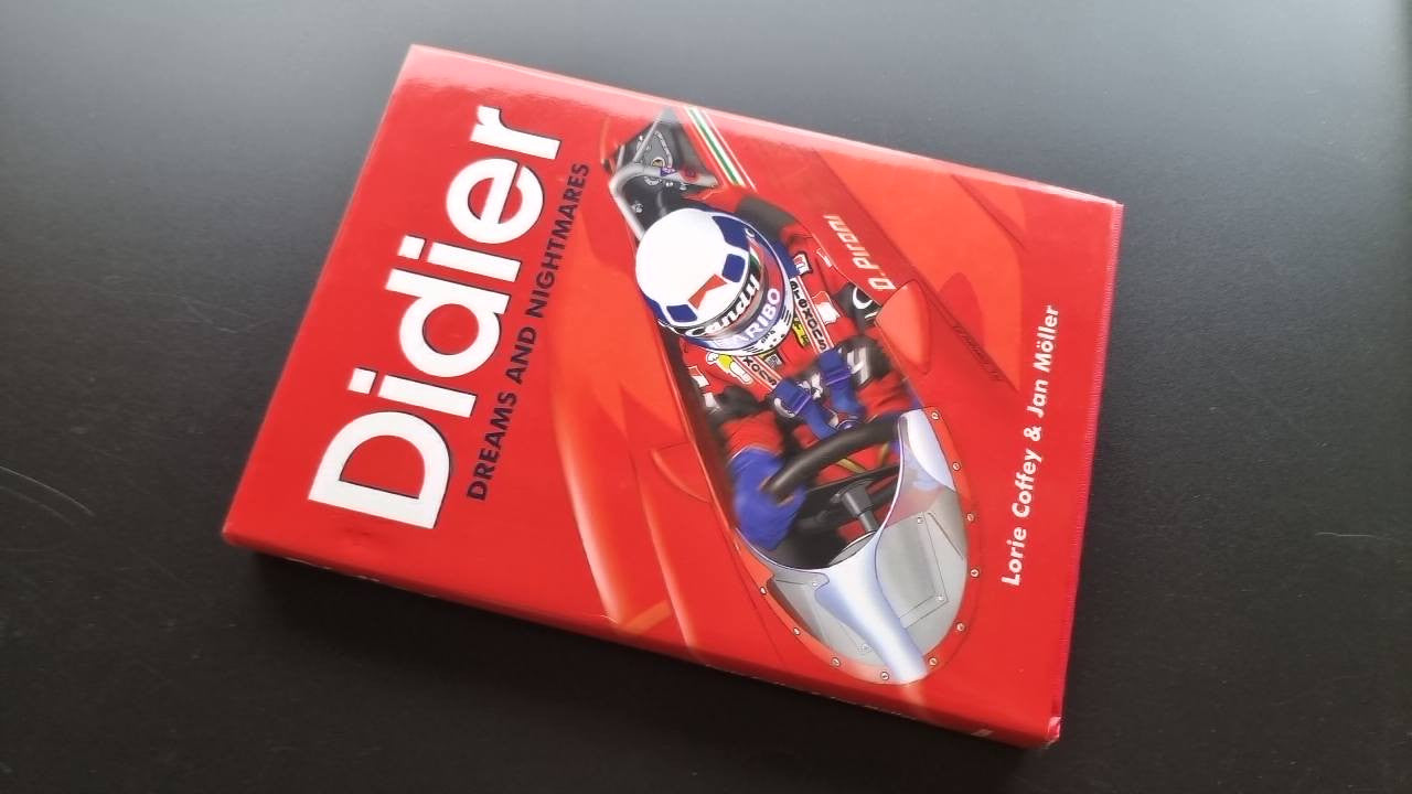 Racing book cover with Didier logo, title text, helmet graphic, and race car.