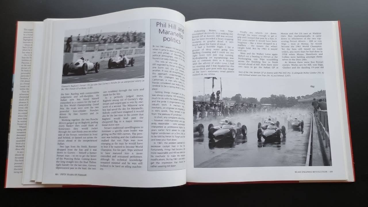 Ferrari racing history book open with Phil Hill section and racetrack photo.