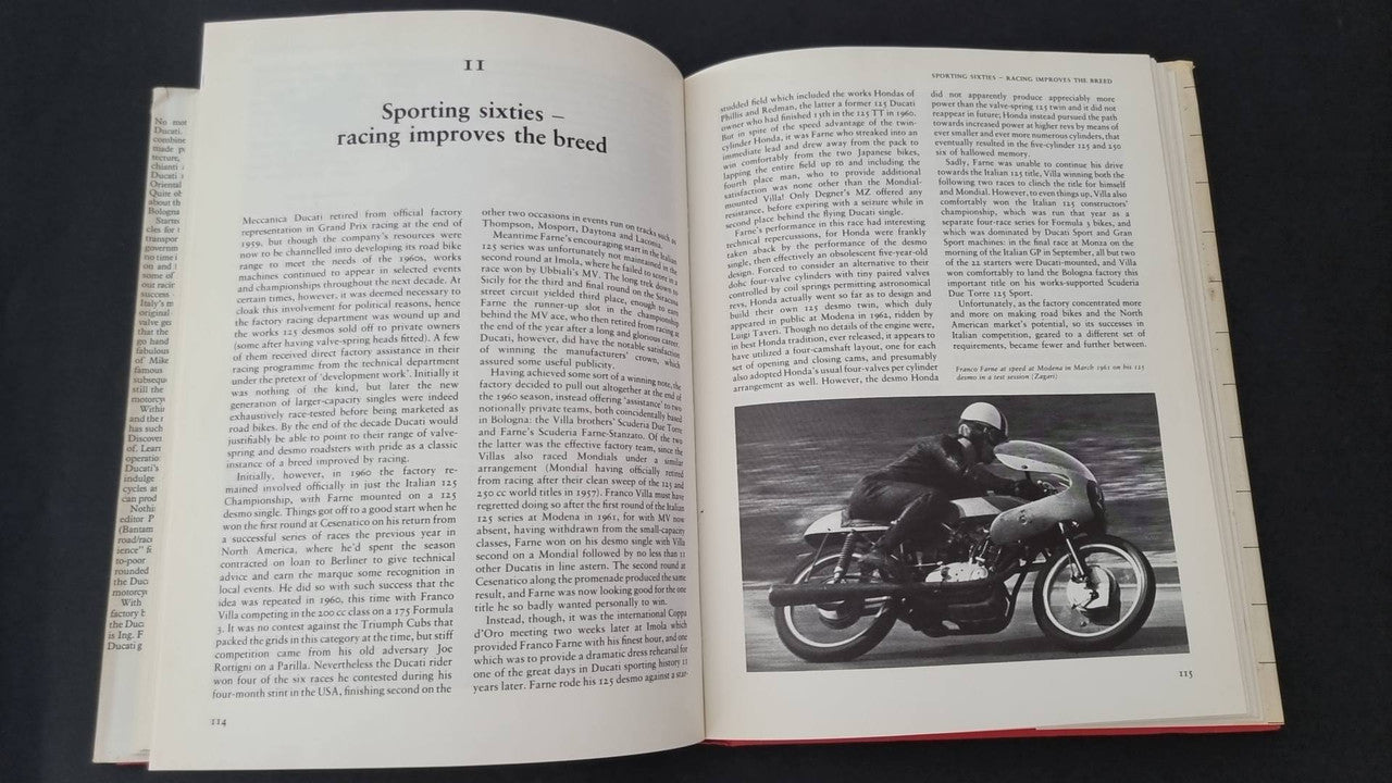 Open motorcycle book pages with racing history text and motorcycle action photo
