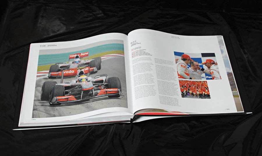 Open racing book showing cars on track and printed article text with photos