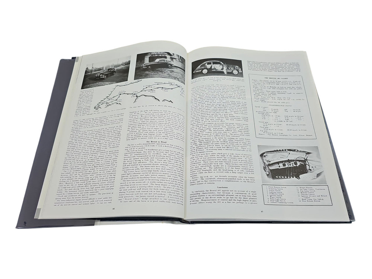 Open hardcover car book with grayscale diagrams and car photos on both pages